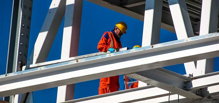 Trabajador de la construcción con uniforme de protección y arnés de seguridad en trabajo en altura